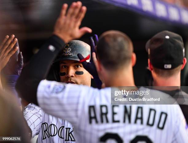 Carlos Gonzalez of the Colorado Rockies is congratulated in the dugout by Nolan Arenado and other teammates after hitting a 2-run homerun against the...