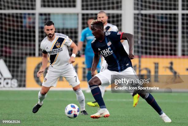 New England Revolution midfielder Wilfried Zahibo watched by Los Angeles Galaxy midfielder Romain Alessandrini during a match between the New England...