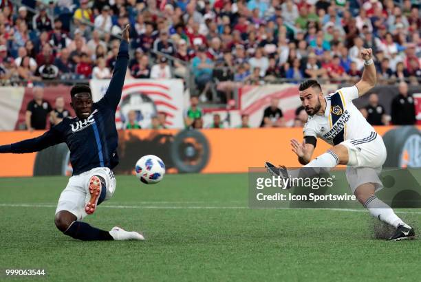 Los Angeles Galaxy midfielder Romain Alessandrini shoots as New England Revolution defender Jalil Anibaba tries to block it during a match between...