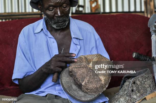 An employee adds some finishing touches to leather hat and shoe made out of tanned fish pelts on June 11 at the Alisam Product Development, a mini...