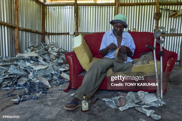 An employee adds some finishing touches to leather hat and shoe made out of tanned fish pelts on June 11 at the Alisam Product Development, a mini...