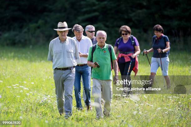 Picture of Winfried Kretschmann, Premier of the state of Baden-Wurttemberg, walking over a meadow with companions during the first day of his 5-day...