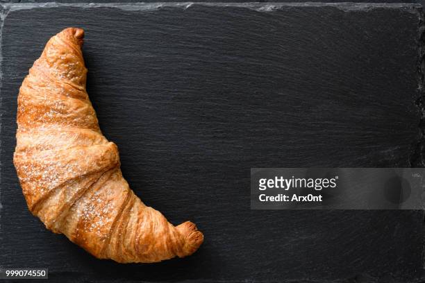 fresh croissant on black slate background - close up bread roll black backdrop horizontal stock pictures, royalty-free photos & images