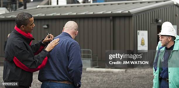 President Barack Obama signs an autograph on a workers back as he tours through V & M Star, a leading producer of seamless pipe for the oil and gas...