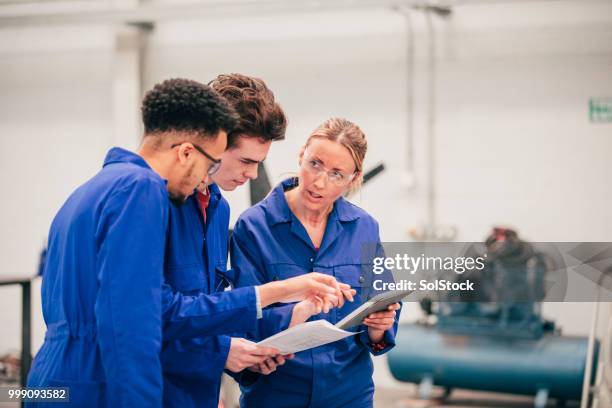 discussing ideas with their engineering tutor - blue jumpsuit stock pictures, royalty-free photos & images