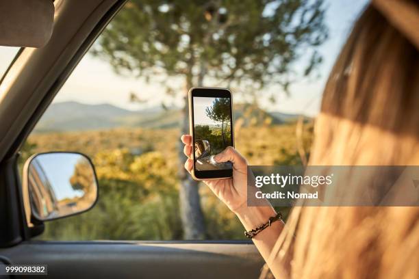 woman taking picture using phone from car window - car photo shoot stock pictures, royalty-free photos & images