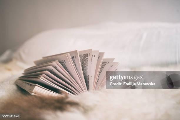 side view of an open book lying on a bed - open book stock-fotos und bilder
