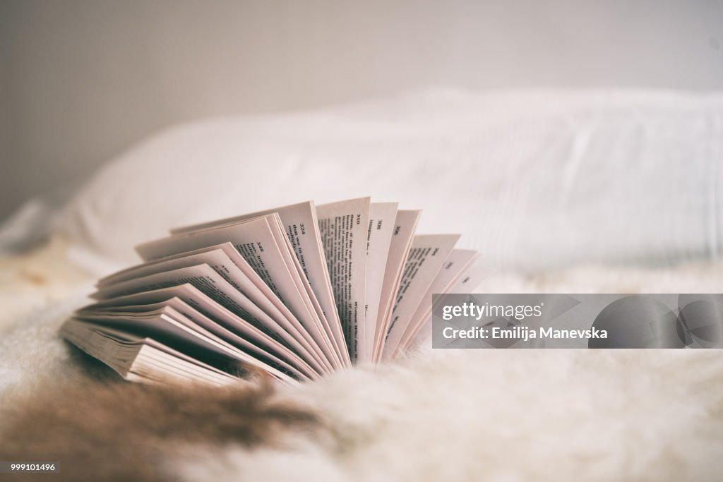 Side view of an open book lying on a bed