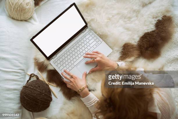 close up of woman sitting on bed using laptop - emilija manevska stock-fotos und bilder