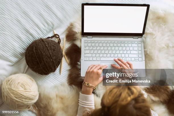 close up of woman sitting on bed using laptop - emilija manevska stock-fotos und bilder