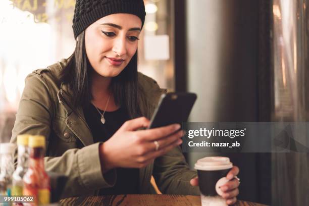 mujer joven con el café en la mano comprobar smartphone. - nazar fotografías e imágenes de stock