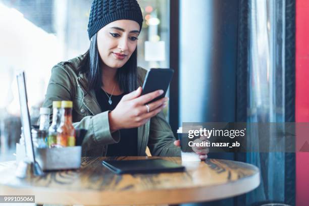 mujer joven con el café en la mano comprobar smartphone. - nazar fotografías e imágenes de stock