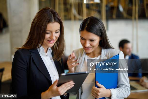 due giovani imprenditrici che discutono di strategia aziendale utilizzando il tablet digitale - emir memedovski foto e immagini stock