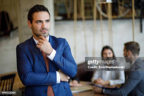 portrait of young businessman with hand on chin - emir memedovski stock pictures, royalty-free photos & images