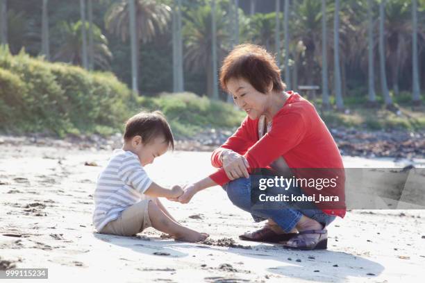 jongen en grootmoeder spelen in het strand - kohei hara stockfoto's en -beelden
