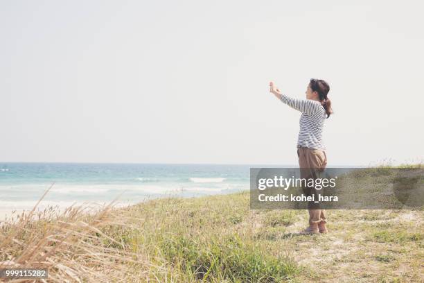 vrouw nemen van een foto door die smartphone aan zee - kohei hara stockfoto's en -beelden