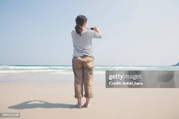 donna che scatta una foto con lo smartphone al mare - kohei hara foto e immagini stock