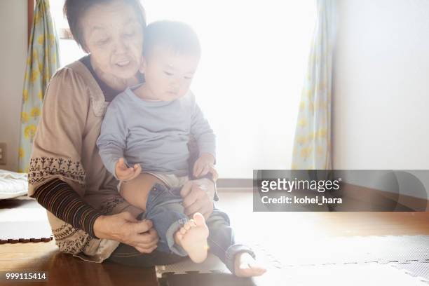 nonna che aiuta suo nipote a cambiare i vestiti - kohei hara foto e immagini stock