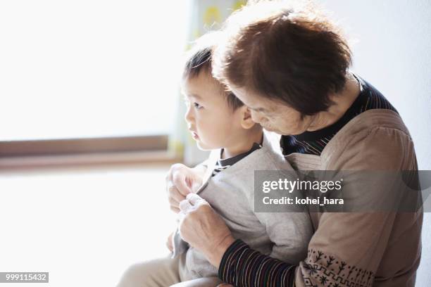 nonna che aiuta suo nipote a cambiare i vestiti - kohei hara foto e immagini stock