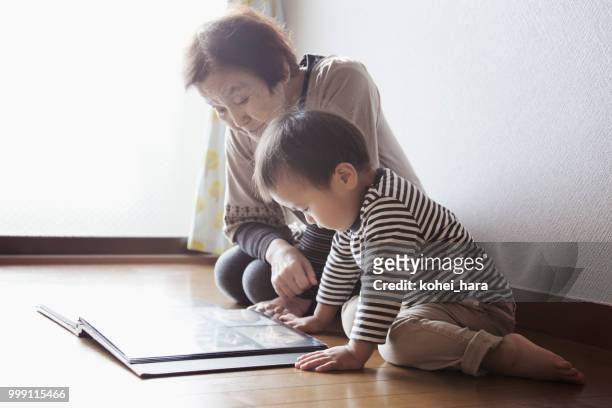 nonna e nipote guardano insieme un album fotografico - kohei hara foto e immagini stock