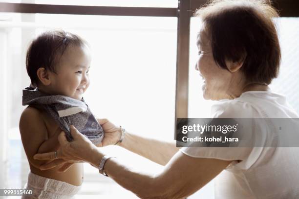 nonna che aiuta suo nipote a cambiare i vestiti - kohei hara foto e immagini stock