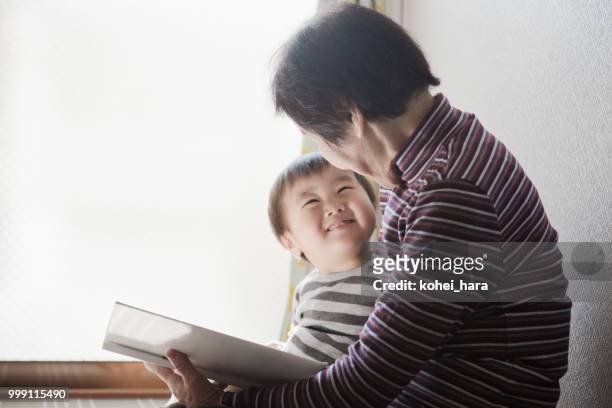 nonna e nipote che leggono insieme un libro illustrato - kohei hara foto e immagini stock