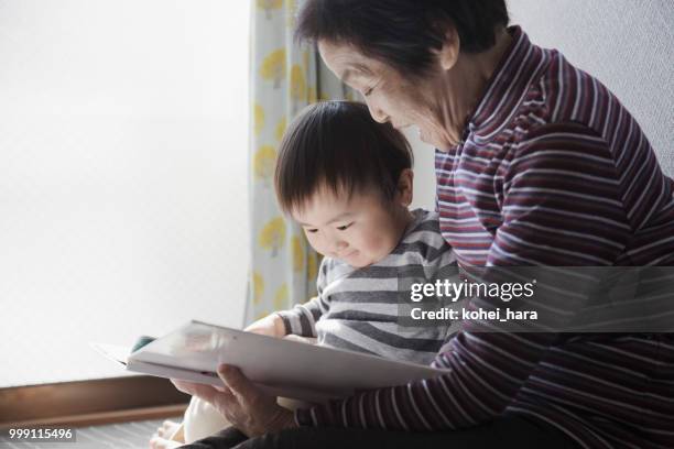 nonna e nipote che leggono insieme un libro illustrato - kohei hara foto e immagini stock