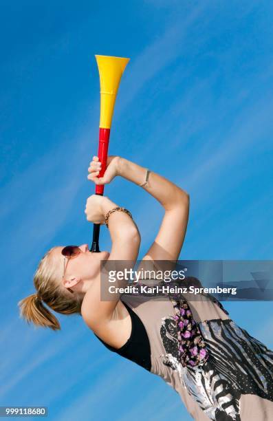 19-year-old woman blowing trumpet, fanfare horn in the colours of the german flag - light skin black woman stockfoto's en -beelden