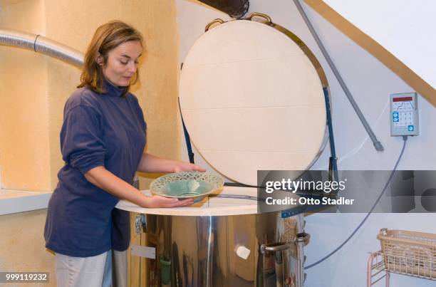 ceramic artist removing fired ceramic items from a kiln, geisenhausen, bavaria, germany - bricolage stockfoto's en -beelden