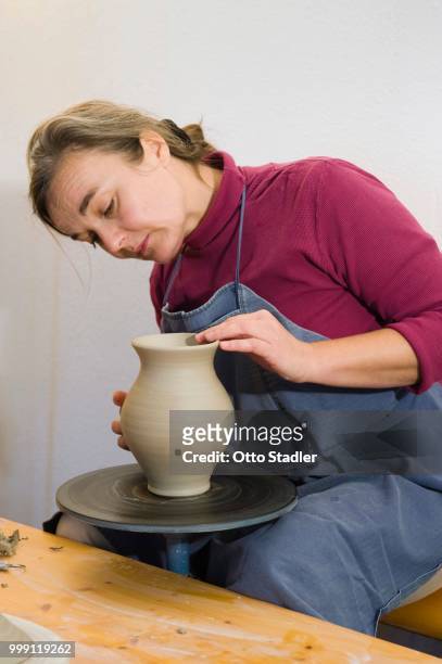ceramic artist working in her workshop with a potter's wheel, polishing the surface of a pitcher, geisenhausen, bavaria, germany - bricolaje stock pictures, royalty-free photos & images