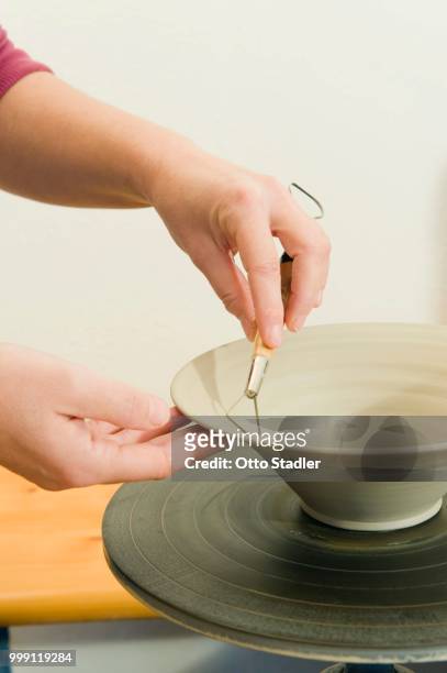 ceramic artist working in her workshop with a potter's wheel, removing excess material while turning, geisenhausen, bavaria, germany - bricolage stockfoto's en -beelden