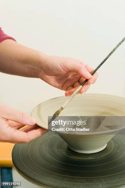 ceramic artist working in her workshop with a potter's wheel, applying a brush pattern, geisenhausen, bavaria, germany - bricolage stockfoto's en -beelden