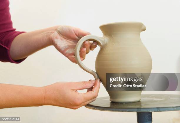 ceramic artist working in her workshop, pulling a handle for a pitcher, geisenhausen, bavaria, germany - bricolage stock-fotos und bilder