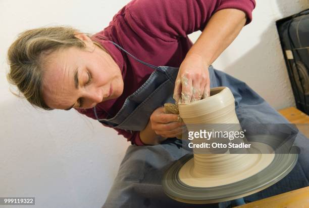ceramic artist working in her workshop with a potter's wheel, pulling a cylinder, geisenhausen, bavaria, germany - bricolage stockfoto's en -beelden