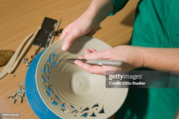 ceramic artist working in her workshop, cutting a pattern into a bowl, geisenhausen, bavaria, germany - bricolage stockfoto's en -beelden