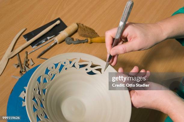 ceramic artist working in her workshop, cutting a pattern into a bowl, geisenhausen, bavaria, germany - bricolage stockfoto's en -beelden