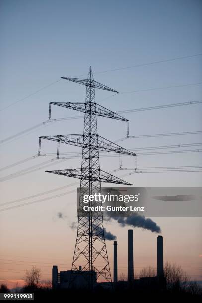 high-voltage power line and a power plant, munich, bavaria, germany - silhouette contre jour stock-fotos und bilder