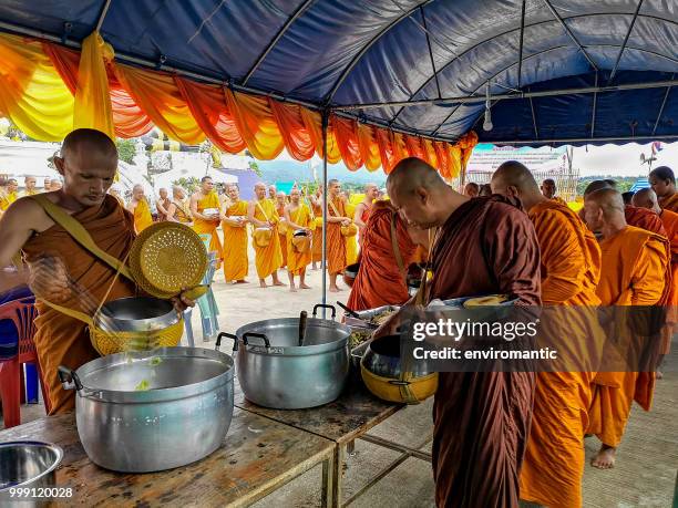 thai buddhist monks serving themselves with food donated and made by laypeople during a merit making buddhist ceremony. - saffron robes stock pictures, royalty-free photos & images