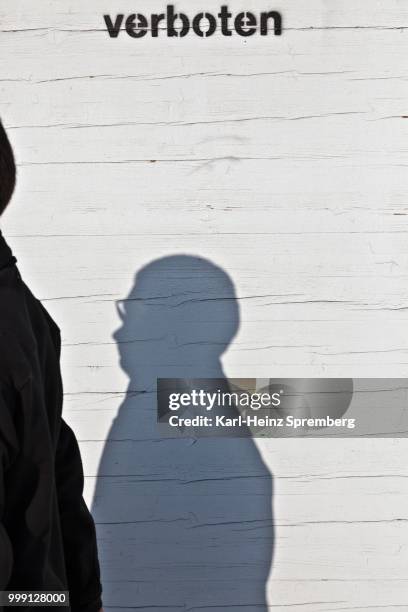 shadow of a man on a wooden site fence, lettering --verboten--, german for --prohibited--, berlin, germany - indication stock pictures, royalty-free photos & images