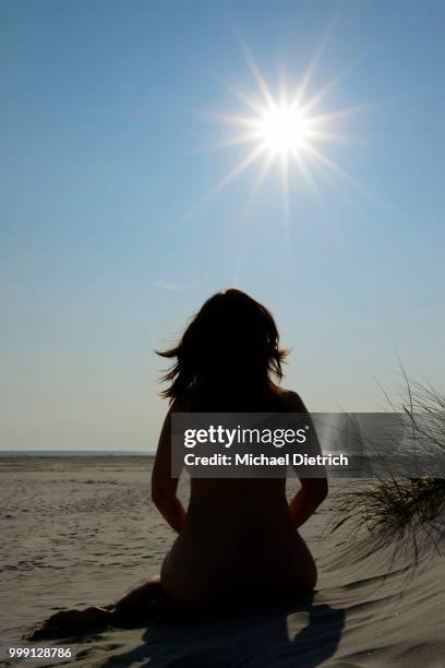 sun-worshipping woman sunbathing in the dunes, nude beach, amrum island, nordfriesland, north frisia, schleswig-holstein, germany - symbolism 個照片及圖片檔