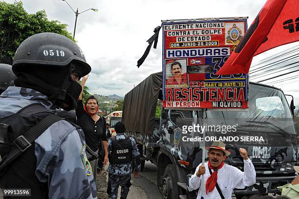 Member of the National Front of Popular Resistance holds a sign with the portrait of former Honduran President Manuel Zelaya in front of a police...