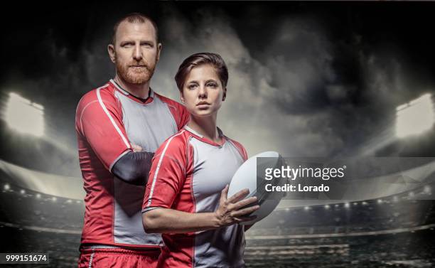 bearded aggressive redhead adult man rugby and beautiful brunette female player in a floodlit stadium - women rugby stock pictures, royalty-free photos & images