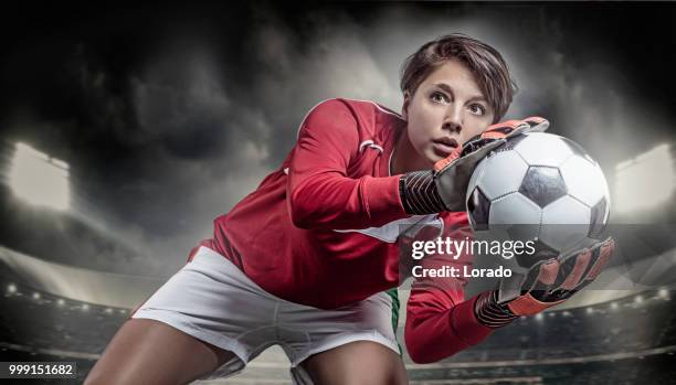 beautiful long haired twenty something soccer player saving a football in a stadium - woman goalie stock pictures, royalty-free photos & images