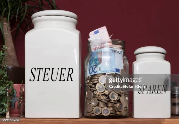 jar containing money and jars with the signs --steuer-- and --sparen--, german for --taxes-- and --savings--, on a kitchen shelf, germany - klein foto e immagini stock