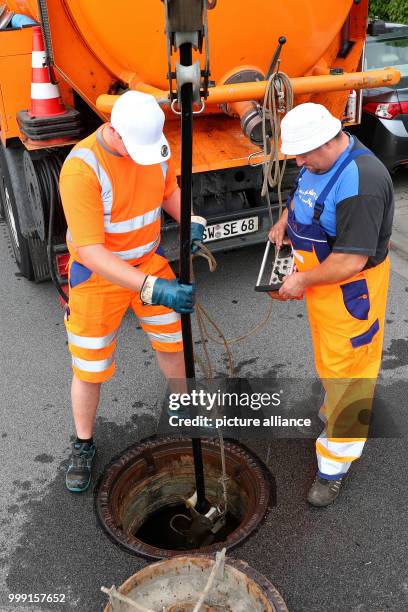 Employees of the municipal drainage operation Schweinfurt pull a high-pressure cleaner into the underground sewerage in Schweinfurt, Germany, 17 July...
