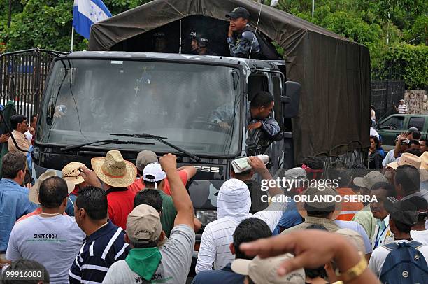 Honduran teachers, students and members of the National Front of Popular Resistance prevent a police vehicle from going through as they demonstrate...