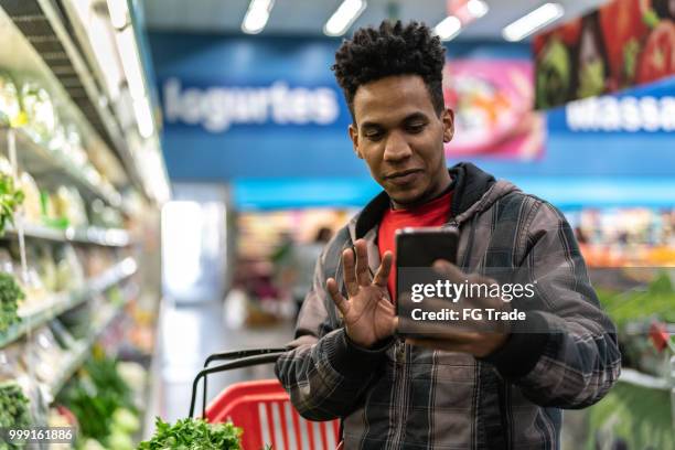 customer making a video chat at supermarket - making a basket imagens e fotografias de stock