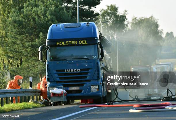 Firefighters in protective suits working on a leaking trailer truck carrying 11,000 liters of nitric acid at the entrance of the Walsleben rest stop...