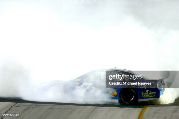 Martin Truex Jr., driver of the Auto-Owners Insurance Toyota, celebrates with a burnout after winning the Monster Energy NASCAR Cup Series Quaker...