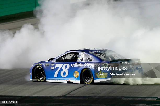 Martin Truex Jr., driver of the Auto-Owners Insurance Toyota, celebrates with a burnout after winning the Monster Energy NASCAR Cup Series Quaker...